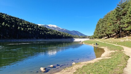Estany d'Engolasters in Andorra with Reflections on Water, Surrounded by Pine Forests and Snow-Capped Mountains