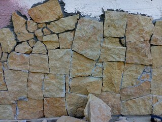 Facing the concrete wall of the house with natural stone. The facade of the house is made of natural materials.