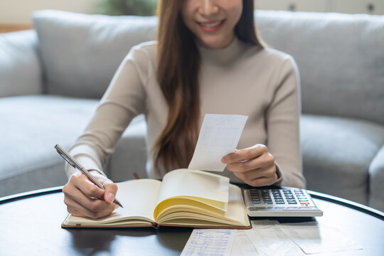 Financial concept asian young business woman hand holding bill, write management budget for saving cost, finance planning to spend enough money on her income for save money, payment tax, investing.
