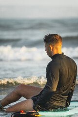 Surfer resting on his surfboard at the beach shore