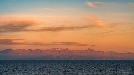 Fototapeta premium Sunset over the snow capped rocky peaks of the mountains of the Mediterranean island of Corsica