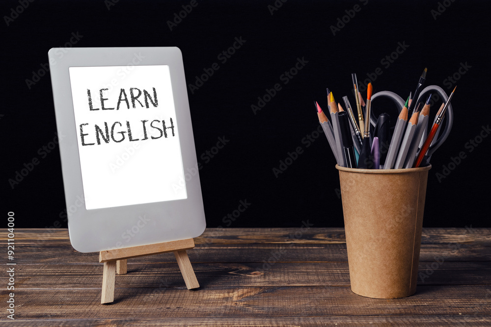 Poster a white tablet with the word learn written on it is on a wooden table