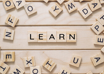 A wooden board with a jumble of letters scattered around it