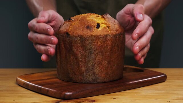 Traditional English Christmas cake tied with a jute thread on the black background. Italian classic Panettone .Pastry Chef sprinkles powdered sugar through a sieve on the fruit Easter cake with