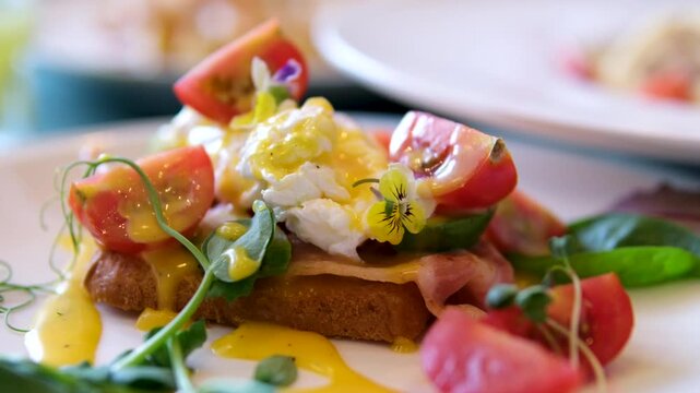 Eggs Benedict with bread and tomato on a plate with becon morning sandwich. Egg benedict with hollandaise sauce and smoked salmon on toast