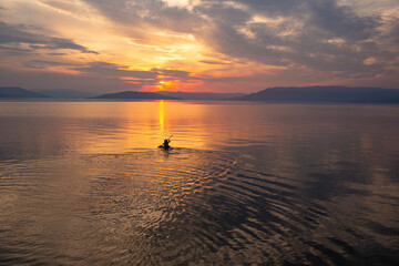 Kayaking off into the sunset on a large mountain lake