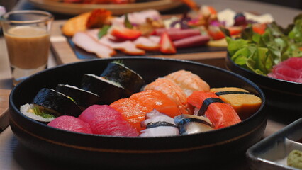 Assorted sushi platter with fresh salmon, tuna, and nigiri rolls served on wooden table, surrounded by other gourmet dishes, emphasizing vibrant Japanese cuisine. Japanese Cuisine and Gourmet Dining.
