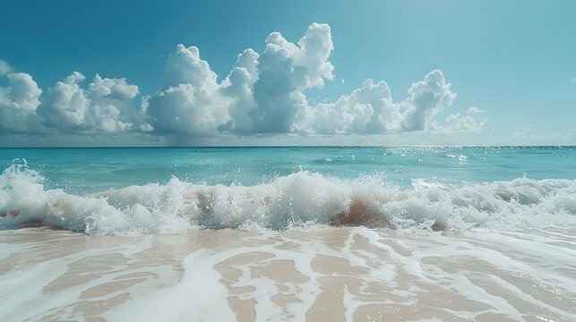  A serene beach setting featuring rolling waves and pristine white cloud-adorned skies