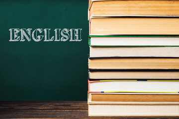 A stack of books with the word English written on the chalkboard behind them