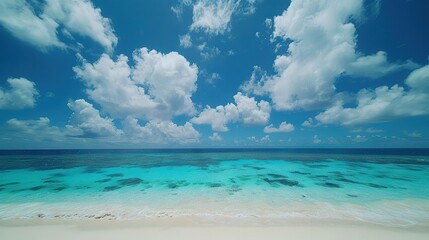 Fototapeta premium A blue beach with crystal-clear water, a cloudy blue sky, and white sand