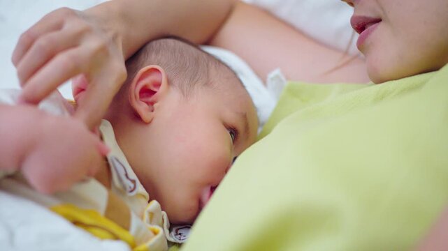 A baby is drinking milk from his mother's breast.