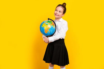 Fototapeta premium Photo of cute schoolgirl hold globe look empty space wear uniform isolated on yellow color background