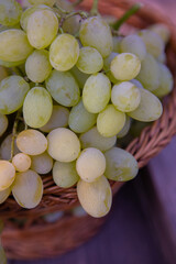 Bunch of white grapes in a basket on a wooden background.
