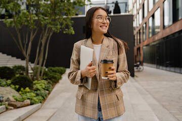 young pretty asian woman walking outside in street doing business