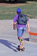 Skateboarder boy wearing backpack skating on outdoors park.