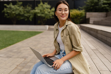 young pretty woman sitting in student campus co-working outside