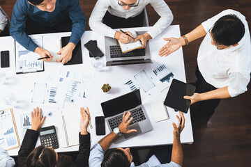 Top view analyst team utilizing BI Fintech to analyze financial data at table in meeting room. Analytic BI dashboard power on paper for business insight and strategic marketing planning. Prudent