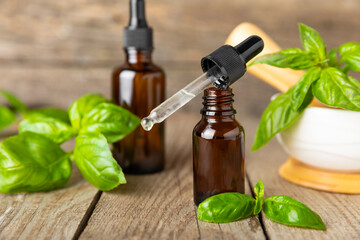 Basil essential oil on a textured wooden background. Basil essential oil and fresh leaves. Aromatherapy. Aroma oil. Medical herbs. Alternative medicine. Place for text. Copy space.