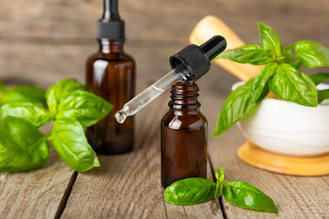 Basil essential oil on a textured wooden background. Basil essential oil and fresh leaves. Aromatherapy. Aroma oil. Medical herbs. Alternative medicine. Place for text. Copy space.