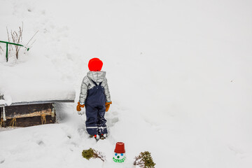 Close-up of boy standing and gazing at snow-covered mountain in garden on frosty winter day. Sweden.