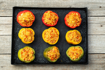 Baked stuffed pepper ( paprika ) with rice , carrot and meat . Top view on rustic background