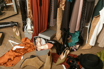 Untidy cluttered woman wardrobe with stylish clothes and accessories. Messy clothes thrown on a...