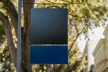 Black metal sign displayed outdoors on a street with copy space