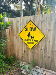 Slow Children & Pets Playing old sign on a wooden fence, verticle