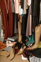 Untidy cluttered woman wardrobe with stylish clothes and accessories. Messy clothes thrown on a...