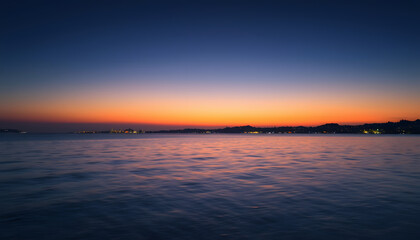 A twilight coastal scene with calm waters and distant city lights under a darkening sky, capturing the peaceful transition from sunset to night isolated with white highlights, png