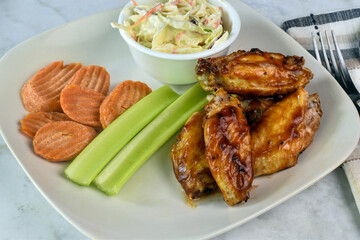 chicken wings top with barbecue sauce with cole slaw