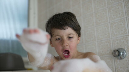 Boy having fun in the bath, playing with soap suds, showing excitement and joy, engaging in imaginative play during bathtime, enjoying water activities, indoor home bathroom setting