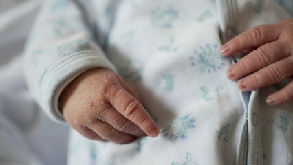Close-up of newborn baby's hands in a white onesie, showcasing tiny fingers and delicate skin texture, innocence and fragility of early life in a peaceful and tender moment