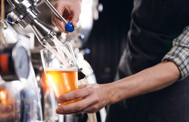 Closeup brewer pours fresh beer from steel tanker at production brewery