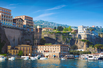 Sunny day in Sorrento, Italy, with multicolored luxury hotels on cliffs above peaceful marina with boats. Sorrento attract lot of tourists from all over world.