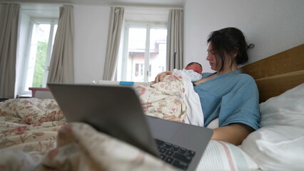 Mother multitasking in bed with a laptop and newborn, balancing work and parenting, yawning and...