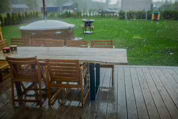 Heavy rain raining on green wooden garden table during summer picnic with no people in shot