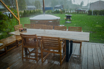 Heavy rain raining on green wooden garden table during summer picnic with no people in shot