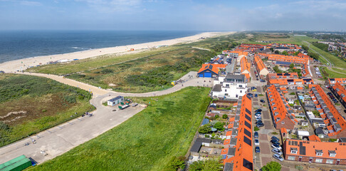 Fototapeta premium The coastal town of Ter Heijde aan Zee features a blend of green fields, sandy beaches, and vibrant rooftops 