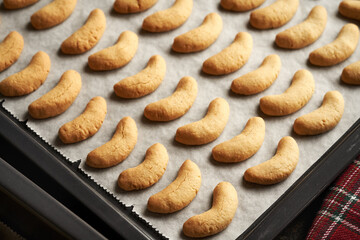 Baked sweet pastry on parchment paper - preparation of homemade vanilla crescents or Kipferl, traditional Christmas cookies