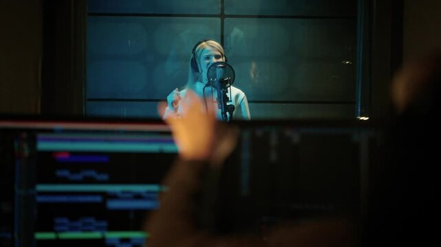 Male studio engineer showing OK symbol to woman singer in recording studio. Professional musicians working together in modern record label, creating new single for music album, talented people team