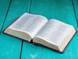 Obraz premium An open book resting on a vibrant teal wooden table under natural light