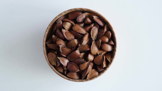 Dried roasted Beech nuts in wooden bowl, top view. 4K Video, rotating motion. Fruits of European beech tree (Fagus sylvatica) used in alternative medicine for improvements in male potency.