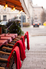 the outdoor cafe is decorated for Christmas, red blankets on the chairs