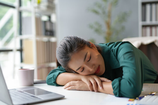 Asian businesswoman is taking a nap at her desk in the office after working too hard