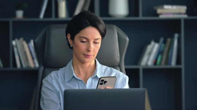 Busy professional woman managing smartphone and phone call at office desk