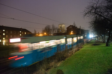 Tram passing a dark stretch of a tram line.