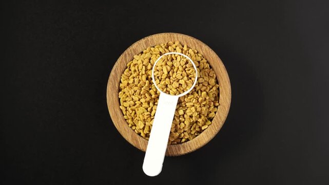 Fenugreek Seeds with measuring scoop. Methi Dana, top view. Shambhala or helba seeds is traditional Indian seasoning. Trigonella foenum-graecum used in culinary and medicine. 