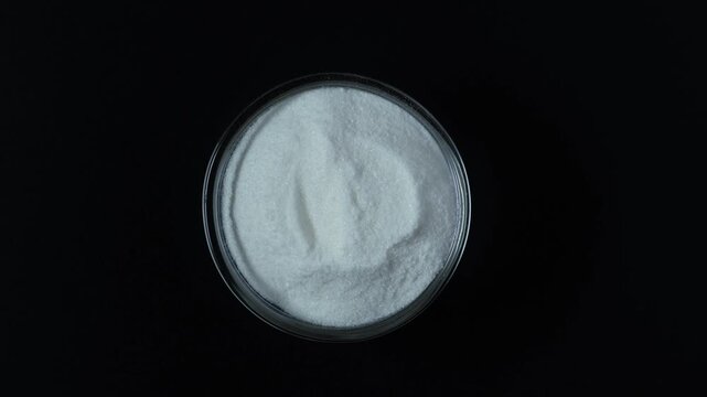 Sodium erythorbate or Sodium isoascorbate in Petri dish, top view. Food additive E316. Sodium erythorbate is produced from sugars derived from different sources, such as beets, sugarcane, and corn.