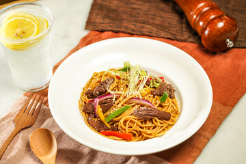 with lemonade, wooden spoon Spaghetti with Shredded Beef with Black Pepper and fork served in plate isolated on napkin and dining table side view of italian food